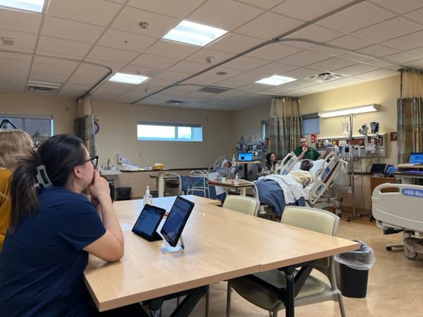 Nursing student monitoring multiple patients from the SimVS Nurse Station central tablet in a university simulation lab
