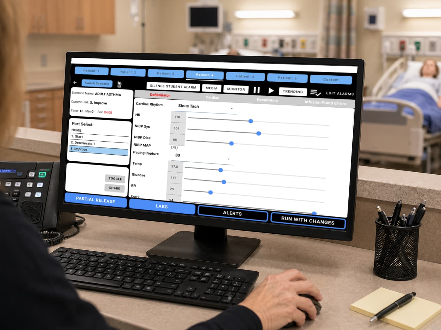 SimVS instructor interface displayed on a monitor at the nurse station with patient tabs, scenario controls, vital sign sliders, and run controls