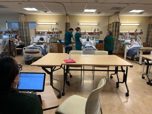 SUNY Brockport simulation lab with nursing students and faculty running multi-patient scenarios